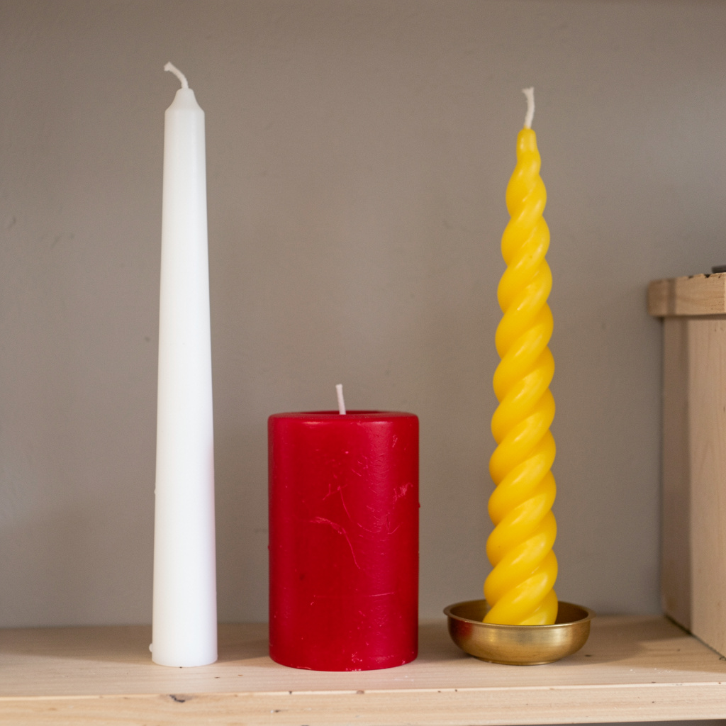 A tall thin white candle, a short fat red candle, and a medi