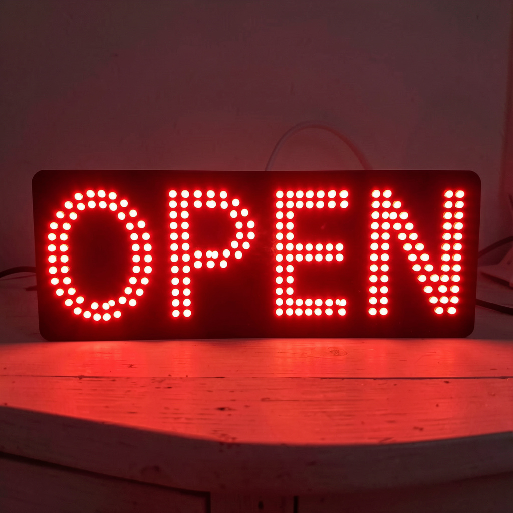 The word 'OPEN' displayed on a red LED sign with glowing pix