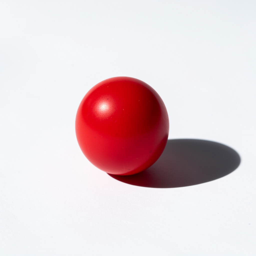 A red sphere on a white surface with a single shadow cast to