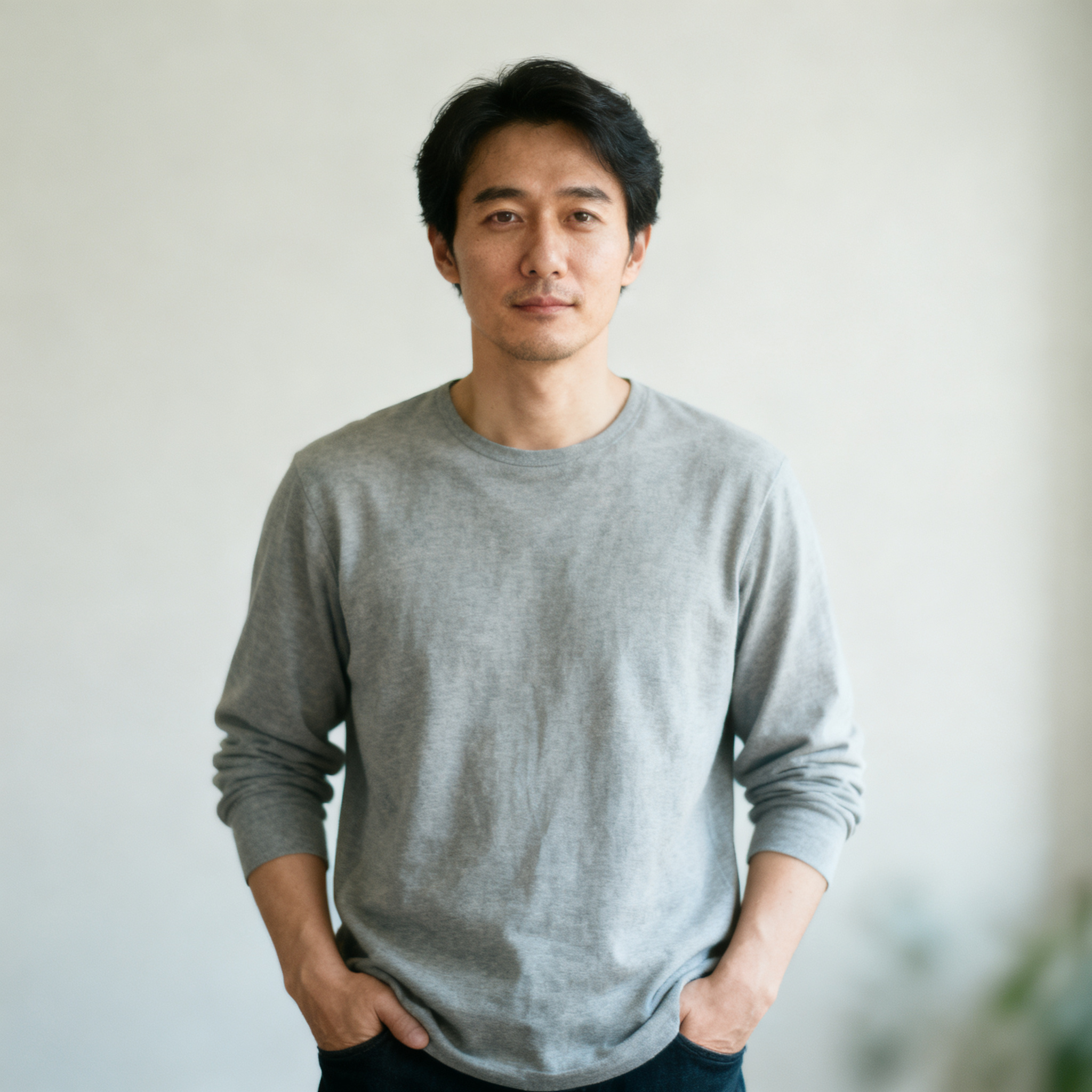 A man standing straight facing the camera, hands in pockets,