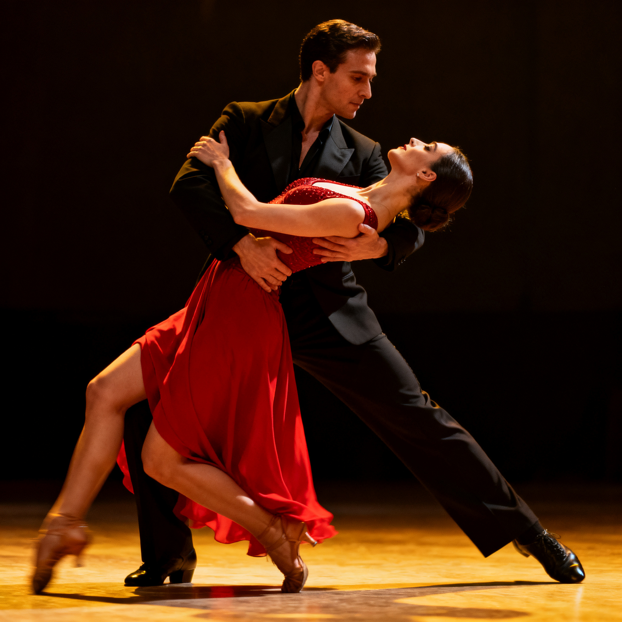 Two tango dancers in a close embrace, the man dipping the wo