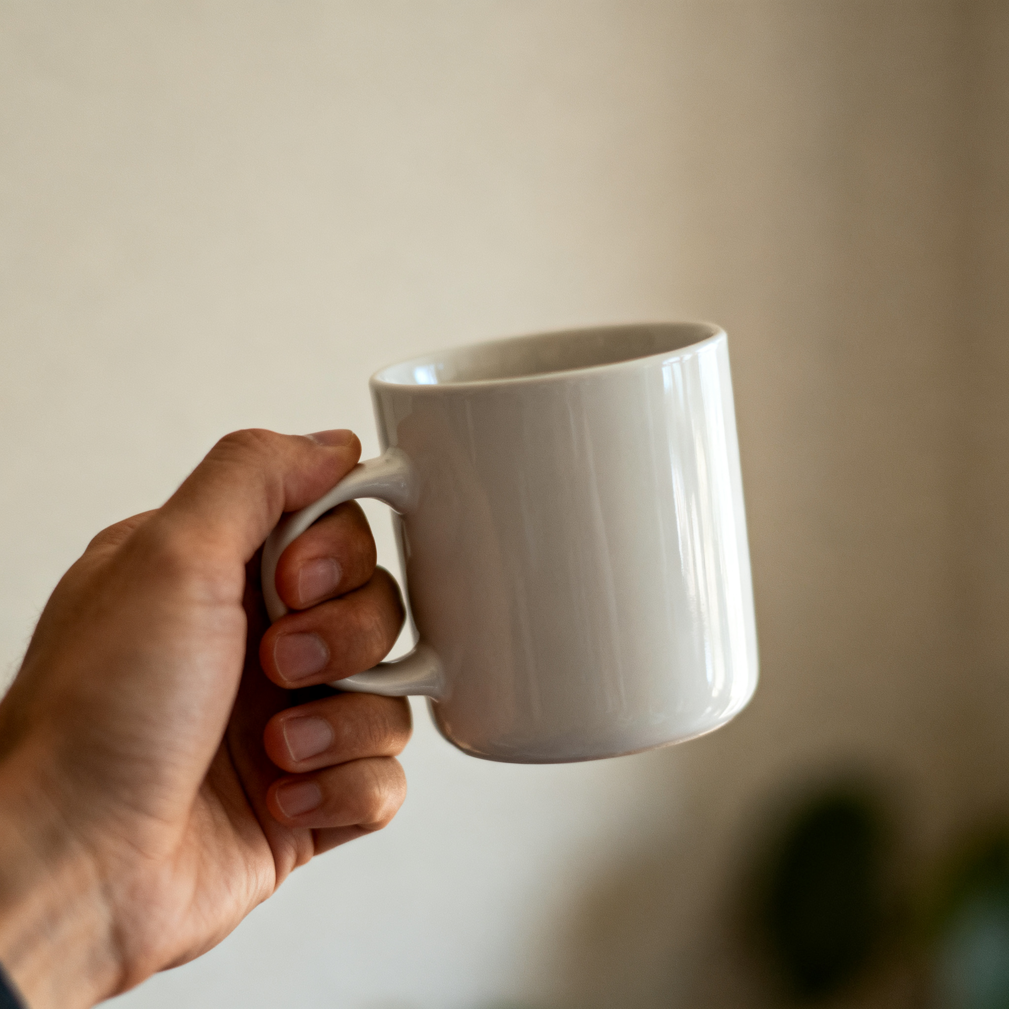 A person holding a white ceramic coffee mug by the handle wi