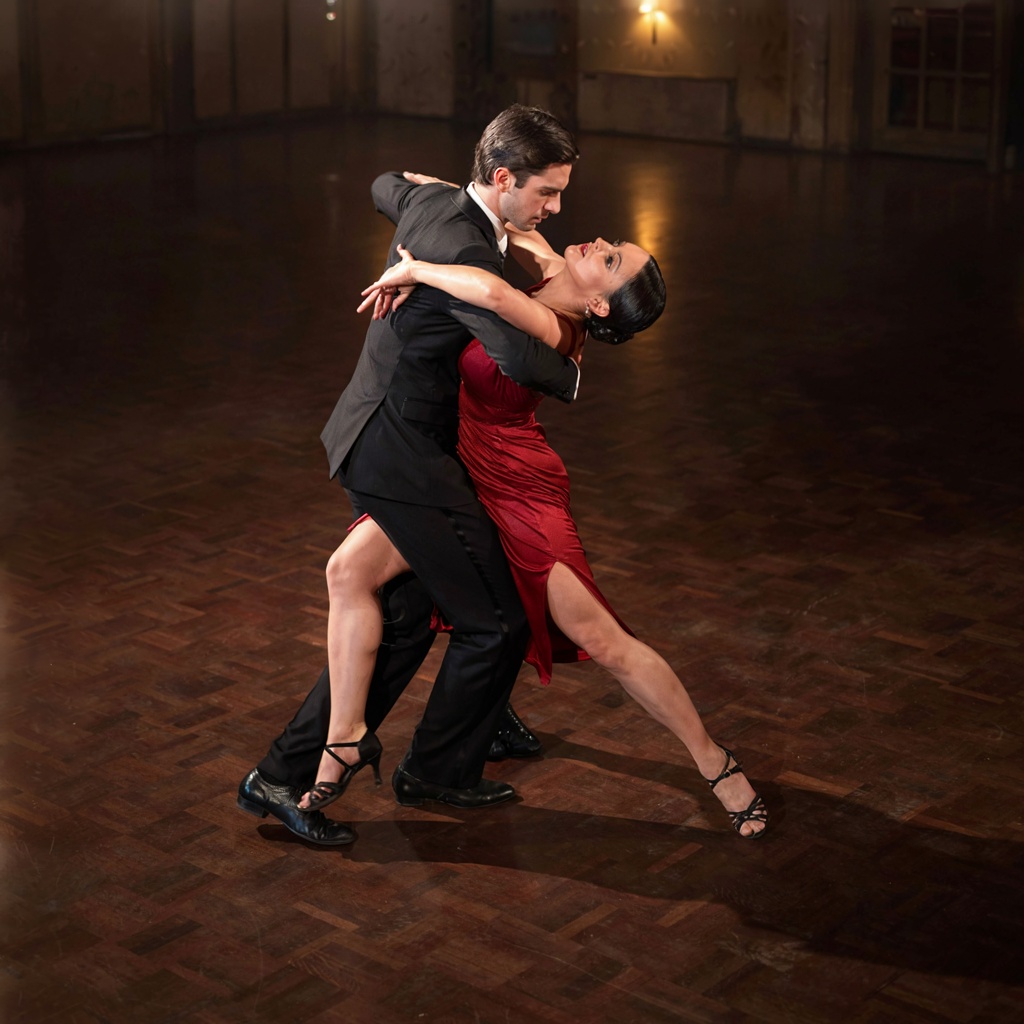 Two tango dancers in a close embrace, the man dipping the wo