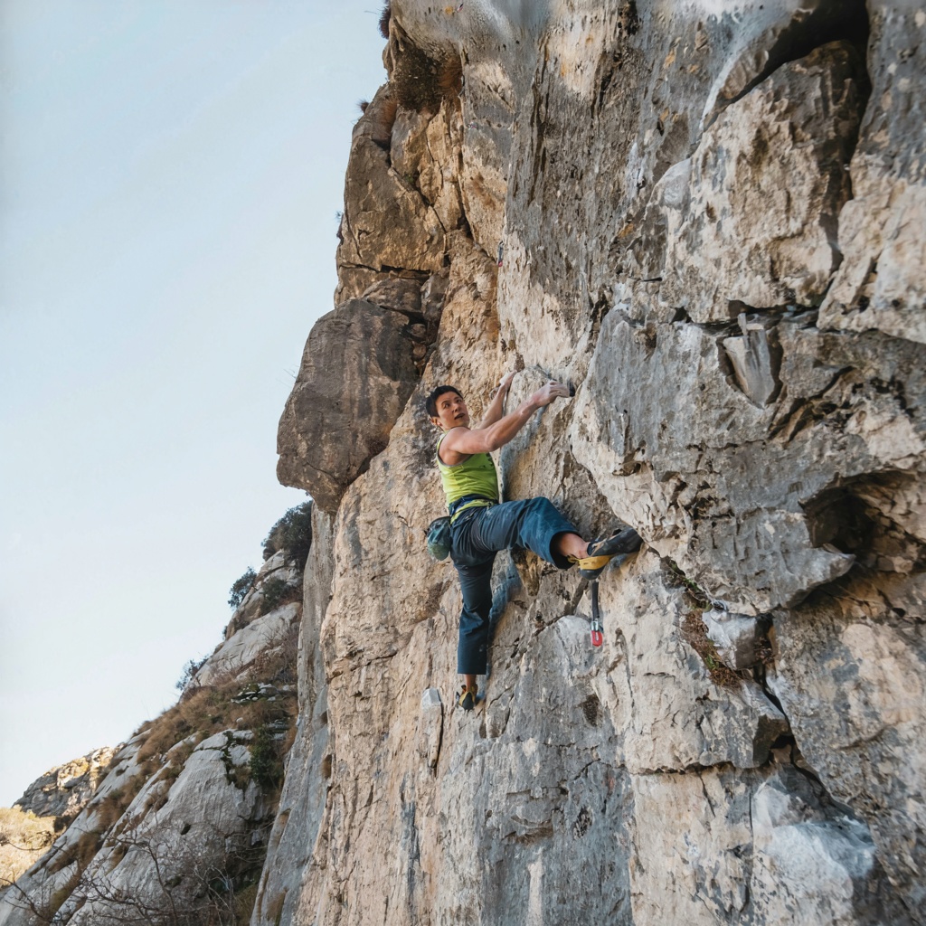 A rock climber clinging to a cliff face with arms and legs e