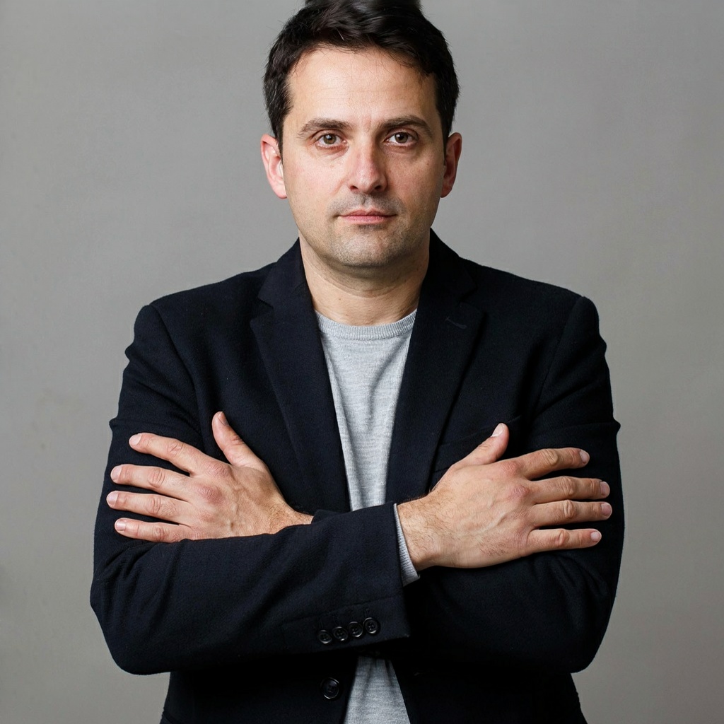 A man with arms crossed, both hands resting on opposite uppe