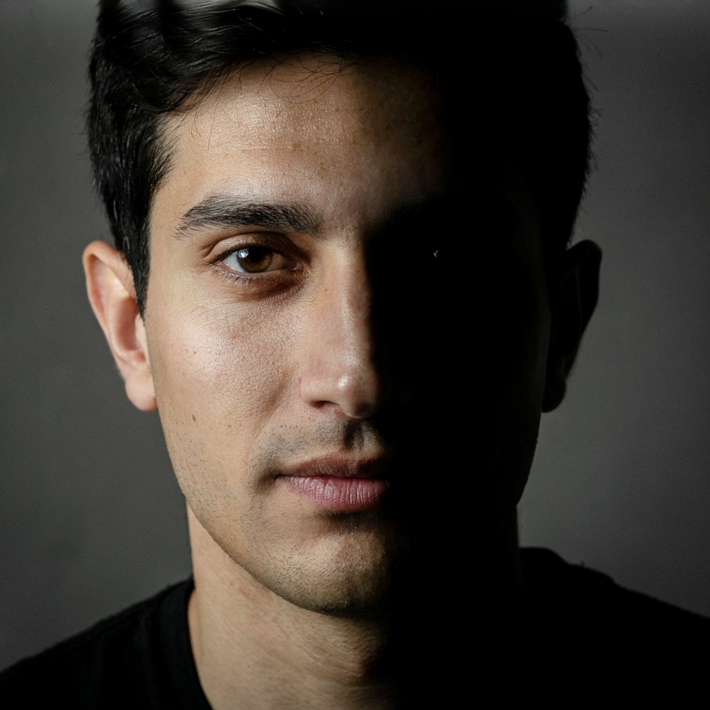 A portrait with dramatic split lighting — half the face brig