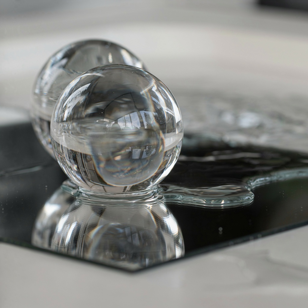 A clear glass sphere sitting on a mirror surface near a pool