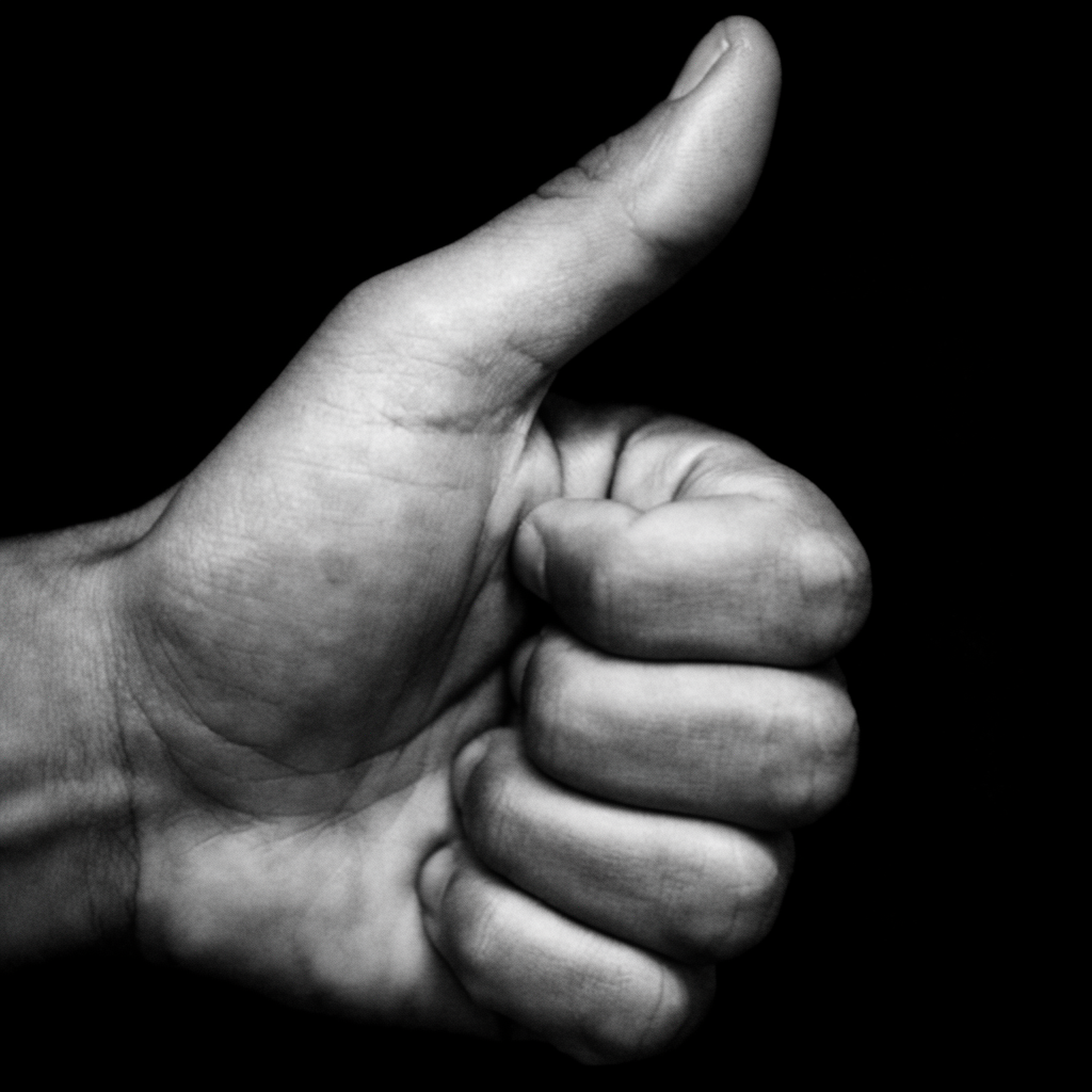 A hand giving a thumbs-up with four fingers curled and thumb