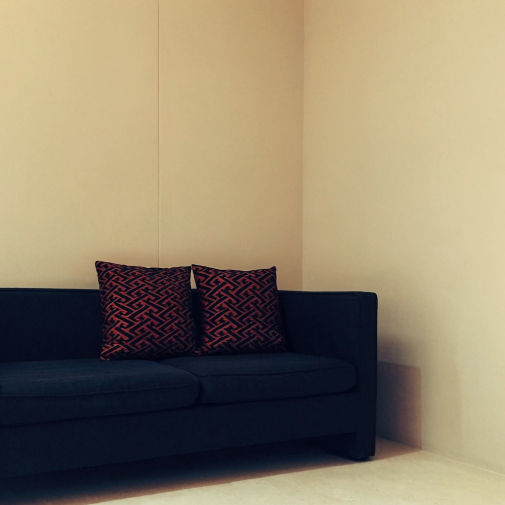 A minimalist room with walls in #F5E6CC (warm cream), a sofa