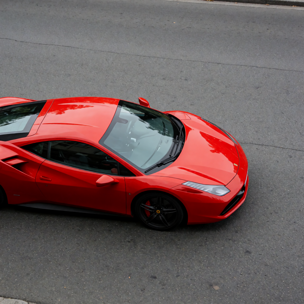 A bright red sports car parked on a gray asphalt road — the 