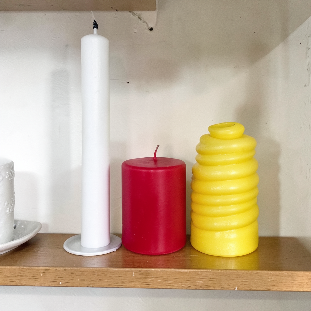 A tall thin white candle, a short fat red candle, and a medi