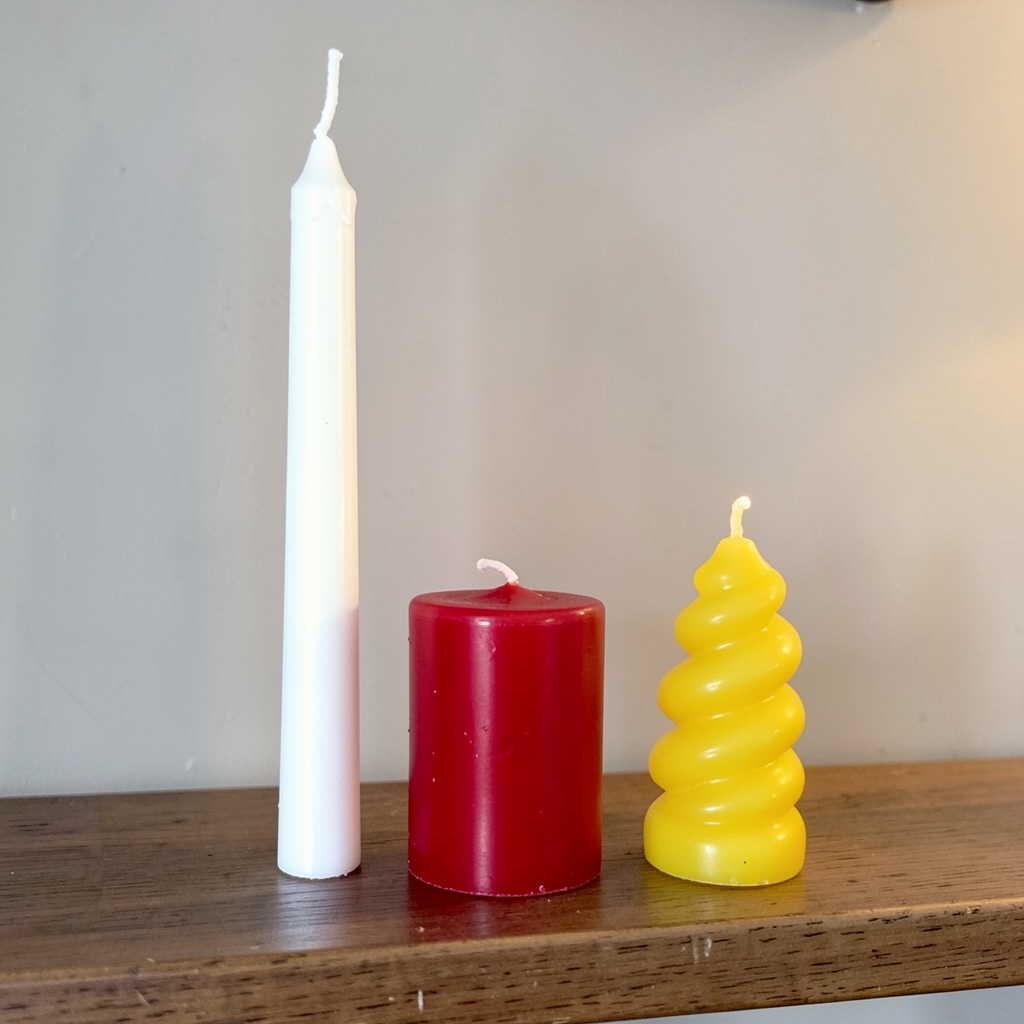 A tall thin white candle, a short fat red candle, and a medi